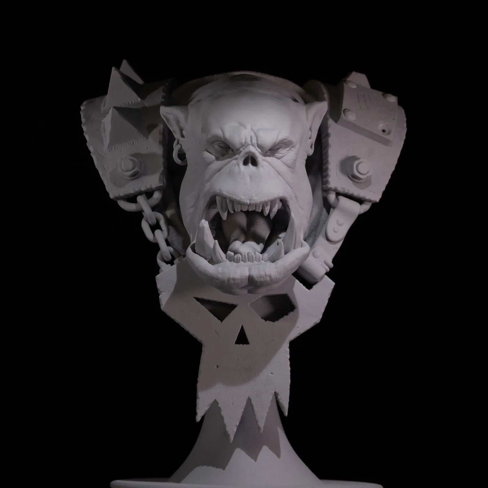Ork bust primed black under dramatic top-down lighting